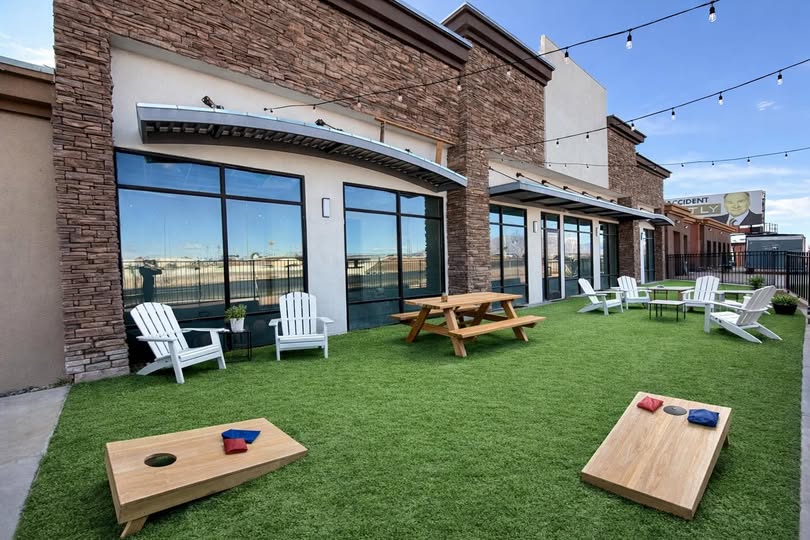 The outdoor courtyard with grass, patio furniture, picnic table and string lights